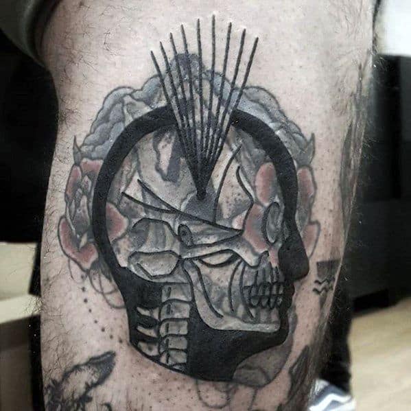 Tattoo of a stylized black skull with flowers, geometric lines, and a blast-over on a leg