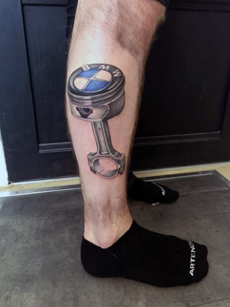 Realistic BMW piston tattoo on calf, featuring detailed shading and the BMW logo for a bold and mechanical automotive design.