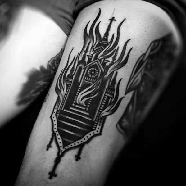 Burning gothic church tattoo with flames rising above steeples. Dark stairs leading up to the entrance on upper arm.