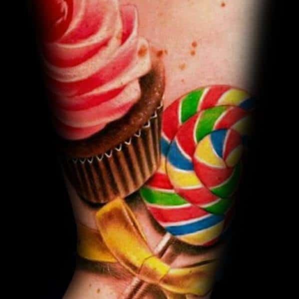 Vibrant candy tattoo featuring a swirled lollipop, cupcake, and golden ribbon, creating a bold and colorful sweet-themed design.
