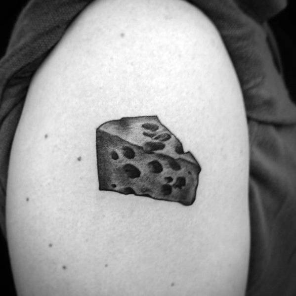 Realistic black and gray cheese tattoo on the upper arm, featuring shading and texture to create a detailed wedge of Swiss cheese.