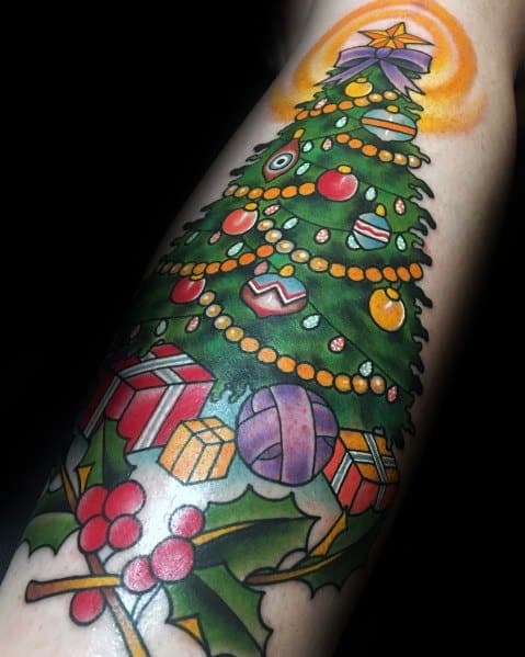 Vibrant Christmas tree tattoo with colorful ornaments, twinkling lights, wrapped gifts, holly leaves, and a glowing star, creating a festive design.