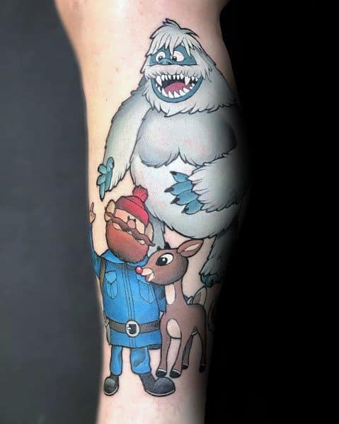 Christmas-themed tattoo featuring Yukon Cornelius, Rudolph the Red-Nosed Reindeer, and the Abominable Snowman from a classic holiday movie.