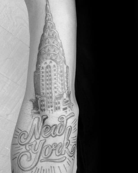 Black-and-grey Chrysler Building tattoo with bold "New York" script, combining architectural detail with a classic lettering style.