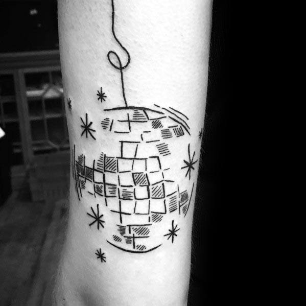 Minimalist disco ball tattoo on a man's forearm with simple black linework, hanging thread detail, and sparkles for a retro vibe.