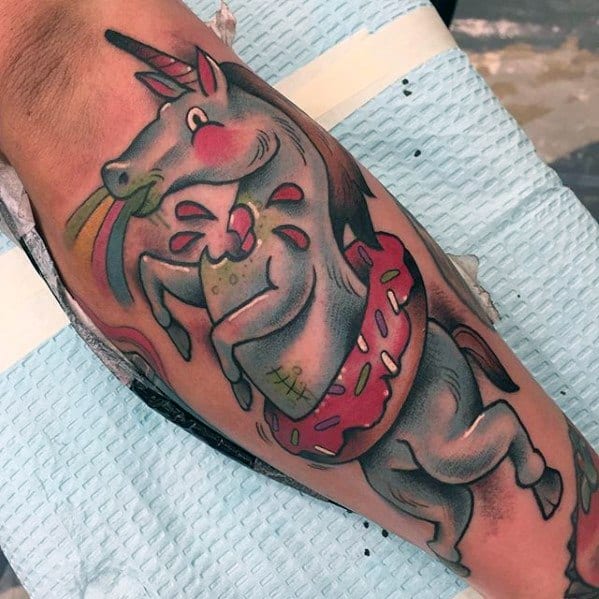 Colorful tattoo of a cartoon unicorn with a donut float, blushing cheeks, and rainbow vomit in a playful, surreal style.