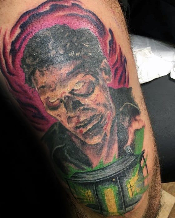 Evil Dead tattoo showing a zombified face with glowing eyes above a haunted cabin surrounded by eerie red and green tones.