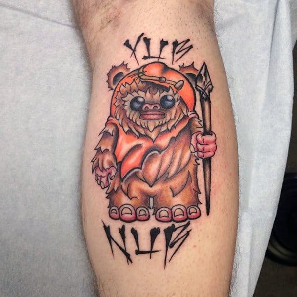 Colorful Ewok tattoo with tribal-style text above and below, featuring a hooded Ewok holding a spear on a man's calf.