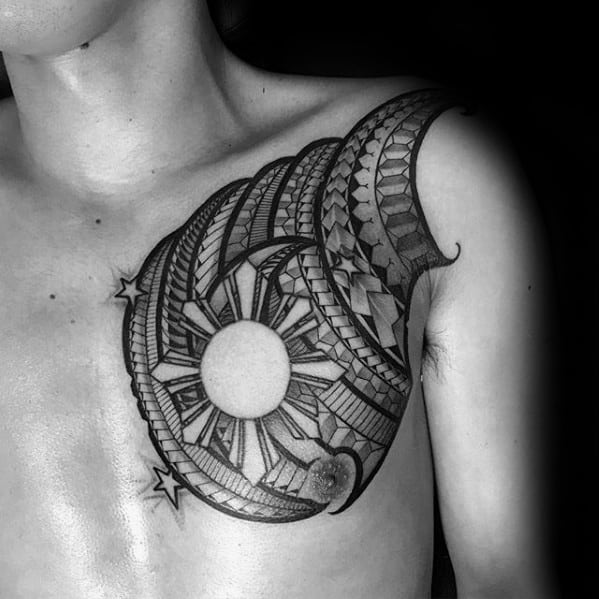 Filipino sun tattoo on the chest with tribal patterns, moon and stars, and bold geometric shading in a crescent composition.