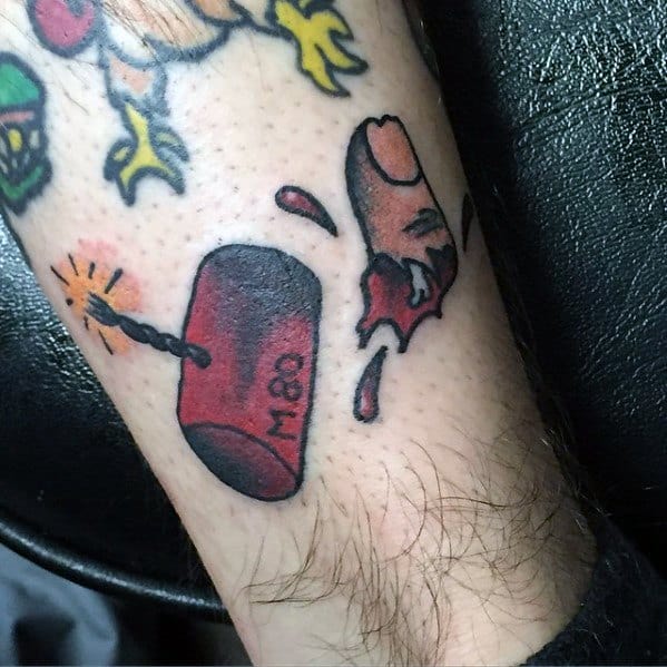 Tattoo of an M-80 firecracker exploding and severing a finger, designed with bold colors and traditional tattoo style.