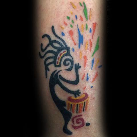 Kokopelli tattoo playing a colorful drum with vibrant bursts of orange, blue, green, and red shooting upward.
