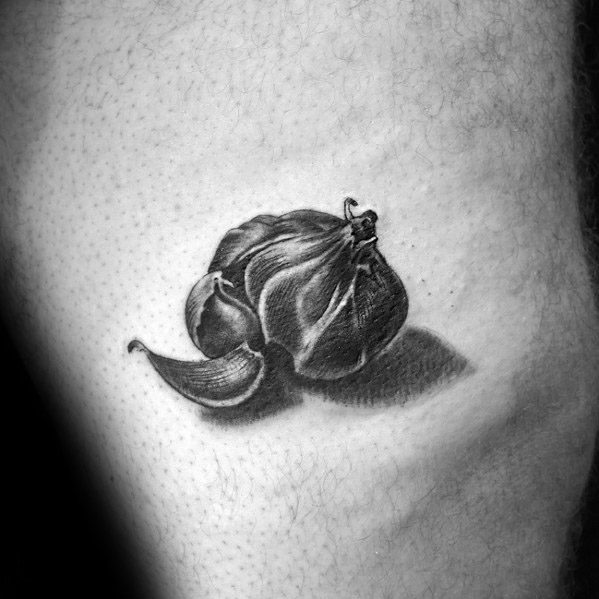 Realistic black and grey garlic tattoo on skin, showcasing detailed shading and texture for a bold and unique design.