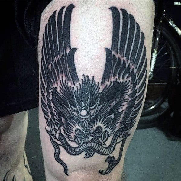Bold Garuda tattoo on the thigh featuring large outstretched wings, fierce facial expression, and a serpent grasped in its claws.