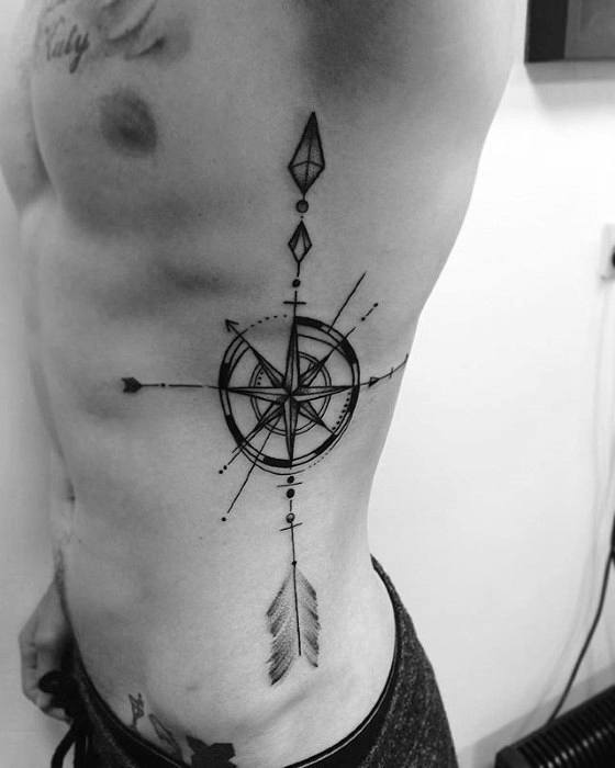 Geometric compass tattoo on ribcage featuring bold lines, arrow details, and diamond shapes in a symmetrical design.