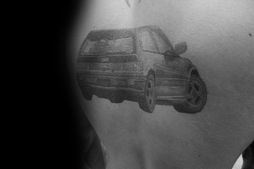 Honda hatchback tattoo on a man's back, featuring a detailed black and gray design of a classic car in motion.