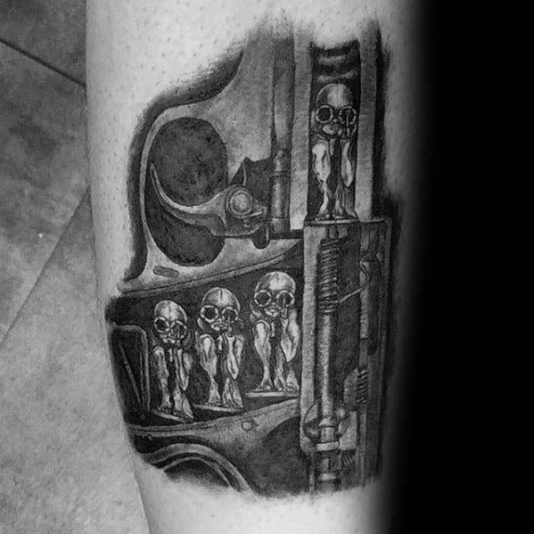 HR Giger-inspired biomechanical tattoo featuring skeletal alien figures embedded in a mechanical structure with detailed shading.