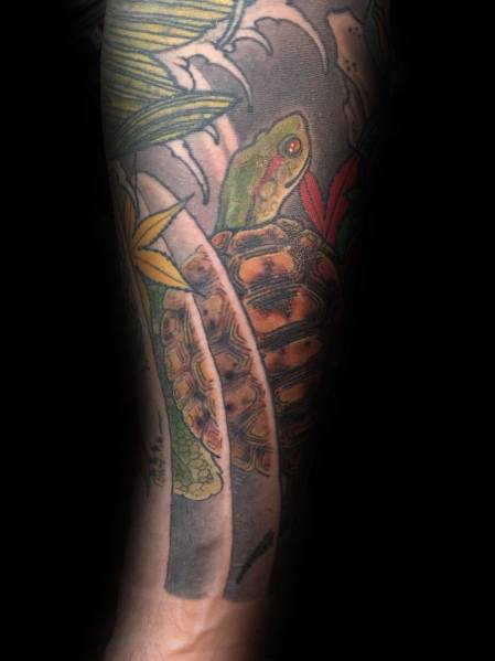 Japanese-style turtle tattoo on a man's leg featuring vibrant details, tropical leaves, and waves for a dynamic, nature-inspired design.