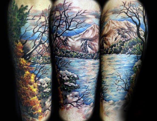 Lake tattoo featuring snowy trees, autumn foliage, and mountains under a bright sky, capturing all four seasons in one scene.
