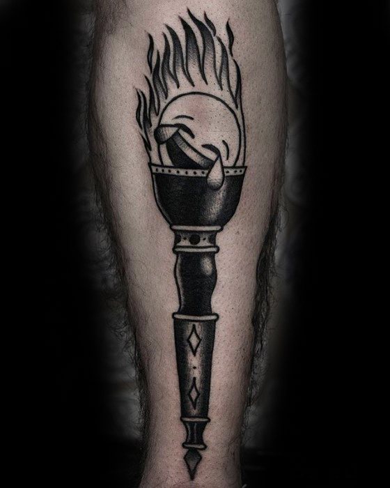 Tattoo of a stylized torch with flame emoji on a person's leg