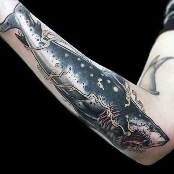 Neo-traditional shark tattoo on forearm with bold lines, white spots, and gold lightning-style accents wrapping around the body.