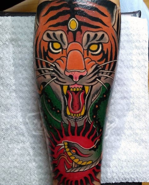 Neo-traditional tattoo featuring a fierce tiger with piercing eyes, a roaring mouth, and a striking red snake intertwined below.