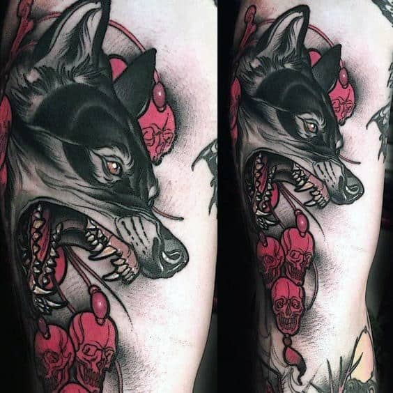 Neo-traditional tattoo of a snarling black wolf with red skull beads, sharp details, and bold shading for a striking and fierce design.