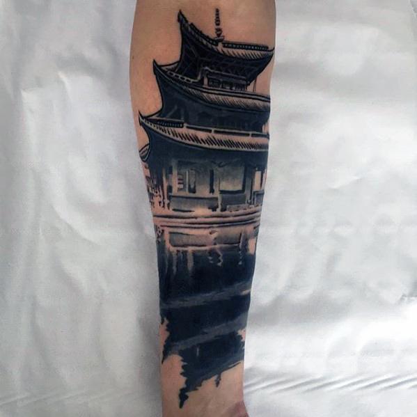 Black and grey pagoda tattoo with realistic reflection in water, covering the forearm in a vertical design.