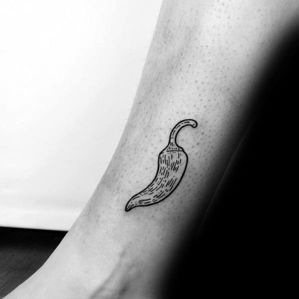Minimalist black ink chili pepper tattoo on the lower leg, featuring fine line details for a sleek and subtle look.