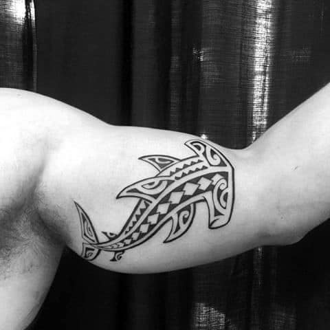 Polynesian shark tattoo on bicep featuring bold tribal patterns and symbolic geometric shapes for strength and protection.