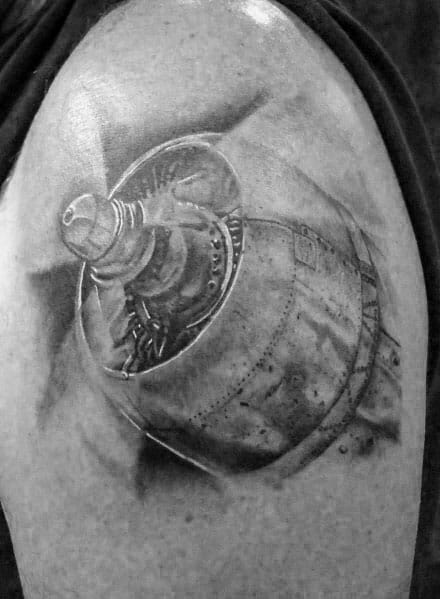 Realistic black and grey tattoo of an aircraft propeller engine on the upper arm, showcasing fine details and shading for depth.