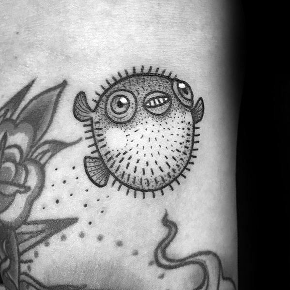 Black and grey pufferfish tattoo with dotwork shading and fine lines, giving it a playful and detailed look on the skin.