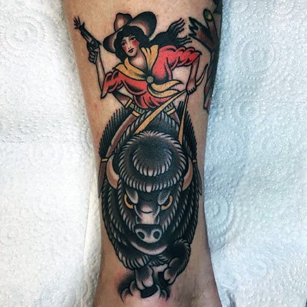 Cowgirl riding a charging bison, holding pistols, in a bold traditional tattoo style with vibrant colors and strong outlines.