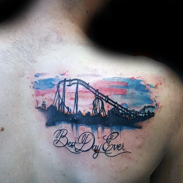 Roller coaster tattoo with watercolor sky and silhouette of a ride, featuring cursive text reading Best Day Ever on upper back.