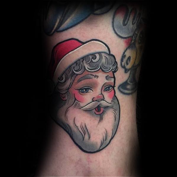 Santa Claus tattoo in traditional style featuring a rosy-cheeked face, fluffy beard, and red hat with a classic vintage look.