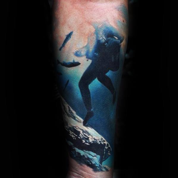 Realistic scuba diver tattoo in deep blue ocean scene with coral reef and fish swimming around.