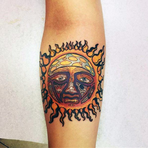Sun tattoo with a tribal-style flaming border and a colorful, surreal face in the center, inspired by Sublime's iconic imagery.