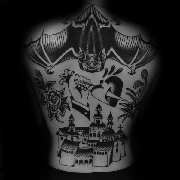 Traditional back tattoo featuring a large bat, dagger through a heart, roses, and a medieval castle in bold black ink.