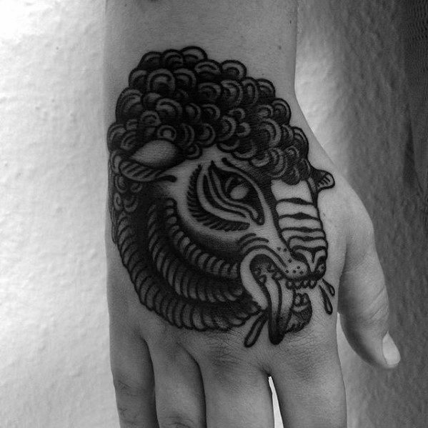 Black and white tattoo of a sheep's head on the back of a person's hand