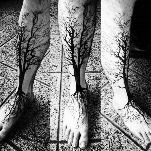 Black ink tree tattoo covering the leg and foot, with intricate branches extending upward and roots wrapping around the ankle in a bold design.