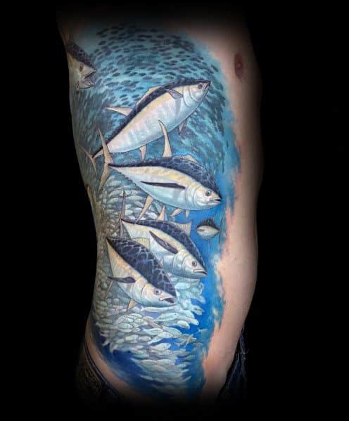 Tuna fish tattoo on a man's side, featuring a detailed underwater scene with a school of fish swimming in shades of blue and silver.