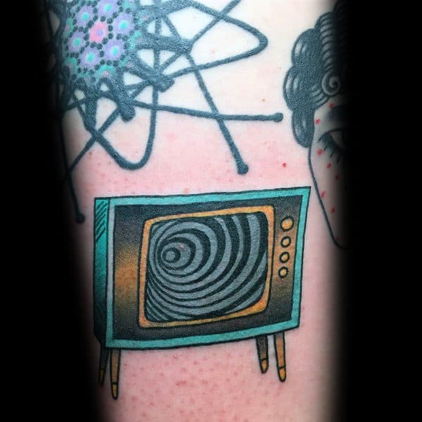 Retro TV tattoo with a hypnotic swirl on the screen, inked in teal and gold with vintage legs, set among abstract and portrait designs.