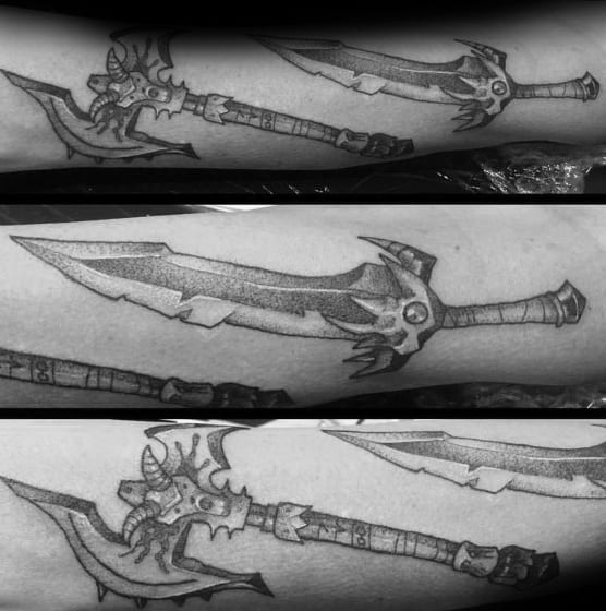 Black and grey tattoo of a World of Warcraft sword, featuring intricate shading and sharp details, inked along the forearm.