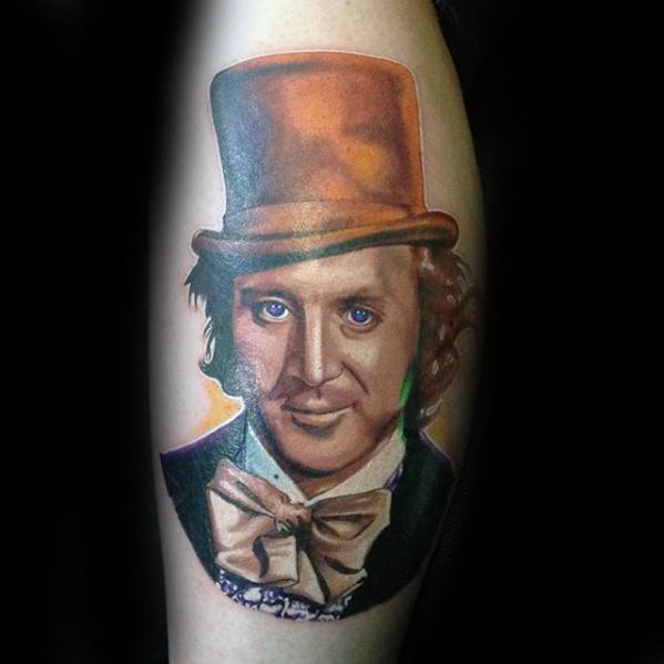 Realistic Willy Wonka tattoo featuring a vivid portrait with a brown top hat, large bow tie, and detailed facial expression.