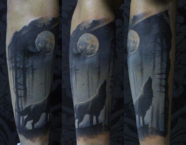 Tattoo of a wolf howling at the moon in a forest setting on an arm