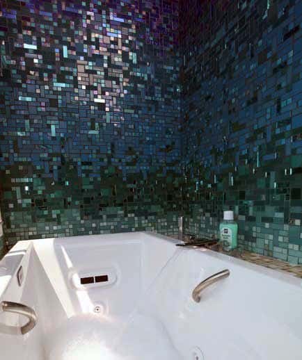 White bathtub with blue-green mosaic tile wall in modern bathroom.