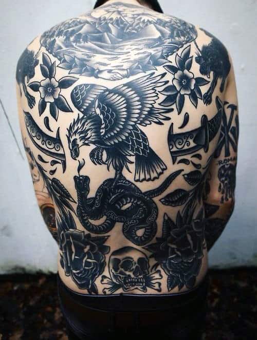 A man with a large back tattoo featuring an eagle, snake, flowers, skulls, and a lion