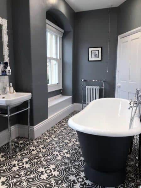 Bathroom with grey walls, a freestanding tub, and patterned tile flooring.