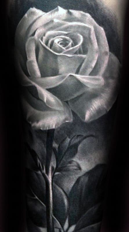 Black and gray tattoo of a realistic rose with detailed petals and leaves