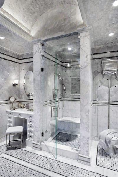 Luxurious marble bathroom with arched ceiling, glass shower, and vanity area.