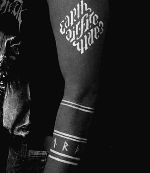 Close-up of arm tattoo with words, stripes, and runic symbols in black and white